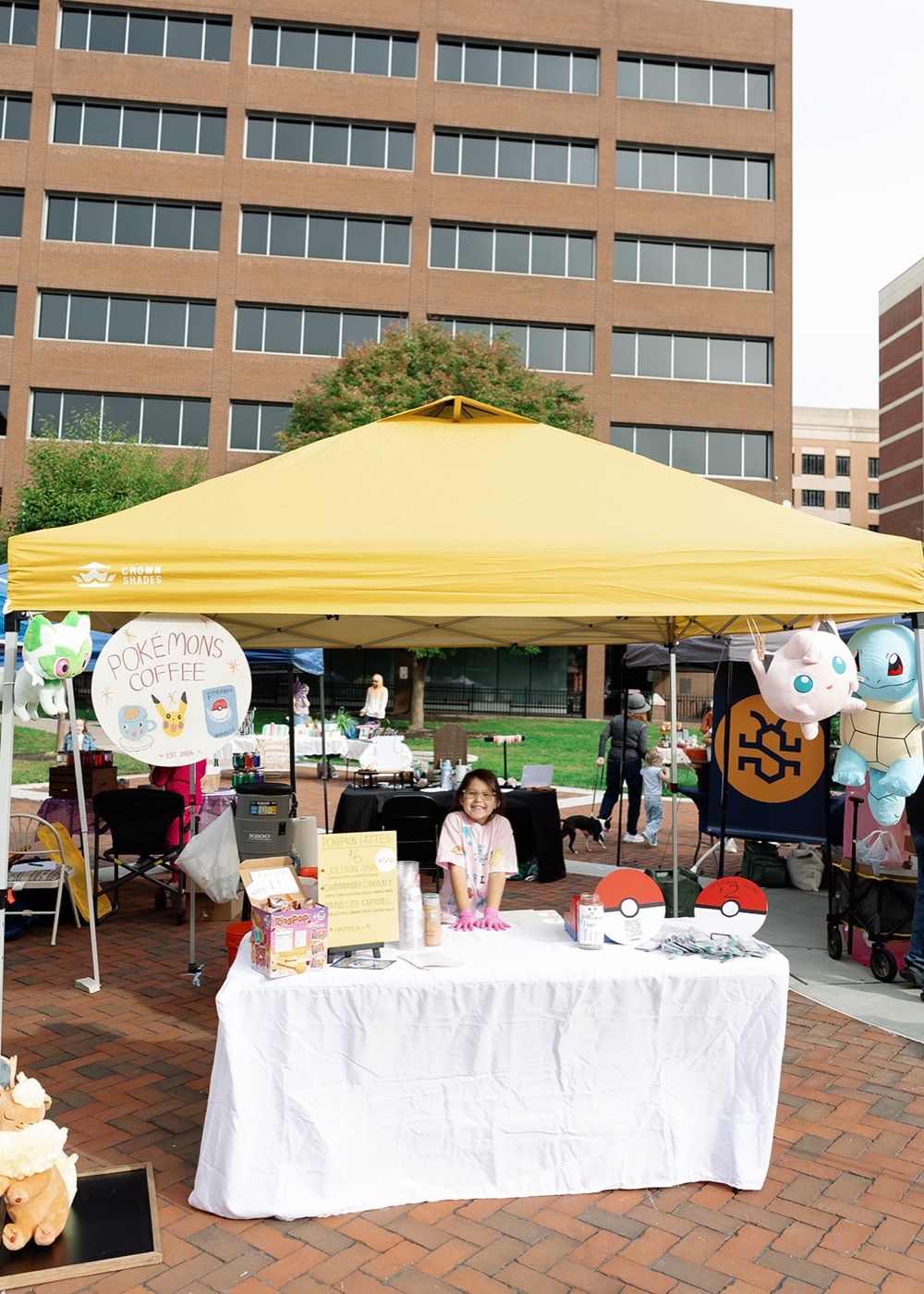The Pokémon Cafe booth under a yellow canopy with a hand-painted sign